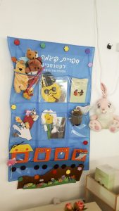 קיר ספריית פיג'מה עם דמויות ירח בפעילות סביב הספר דוד ירח בשמים במעון בית פרידה ברמלה