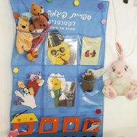 קיר ספריית פיג'מה עם דמויות ירח בפעילות סביב הספר דוד ירח בשמים במעון בית פרידה ברמלה