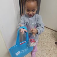 ילדה שמחה עם המתנה החדשה במעון אמונה חדרה